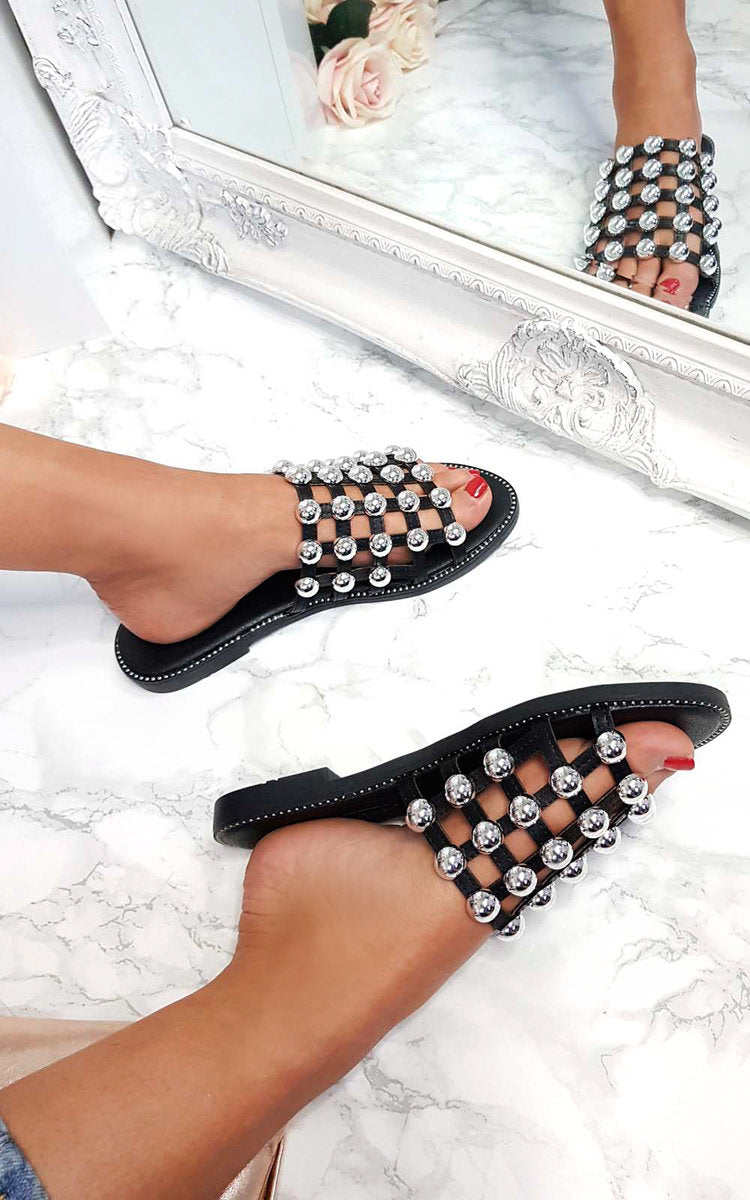 Black studded flat slides with silver lattice straps, open-toe view