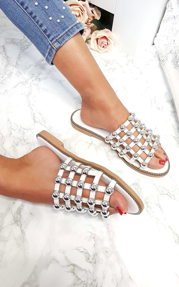 Studded lattice flat slide sandals on feet, jeweled cross-lattice straps, tan sole
