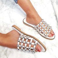 Studded lattice flat slide sandals on feet, jeweled cross-lattice straps, tan sole