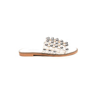 White flat slide sandals with silver studded lattice strap over the toe