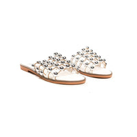 White flat slide sandals with studded lattice straps and open toe