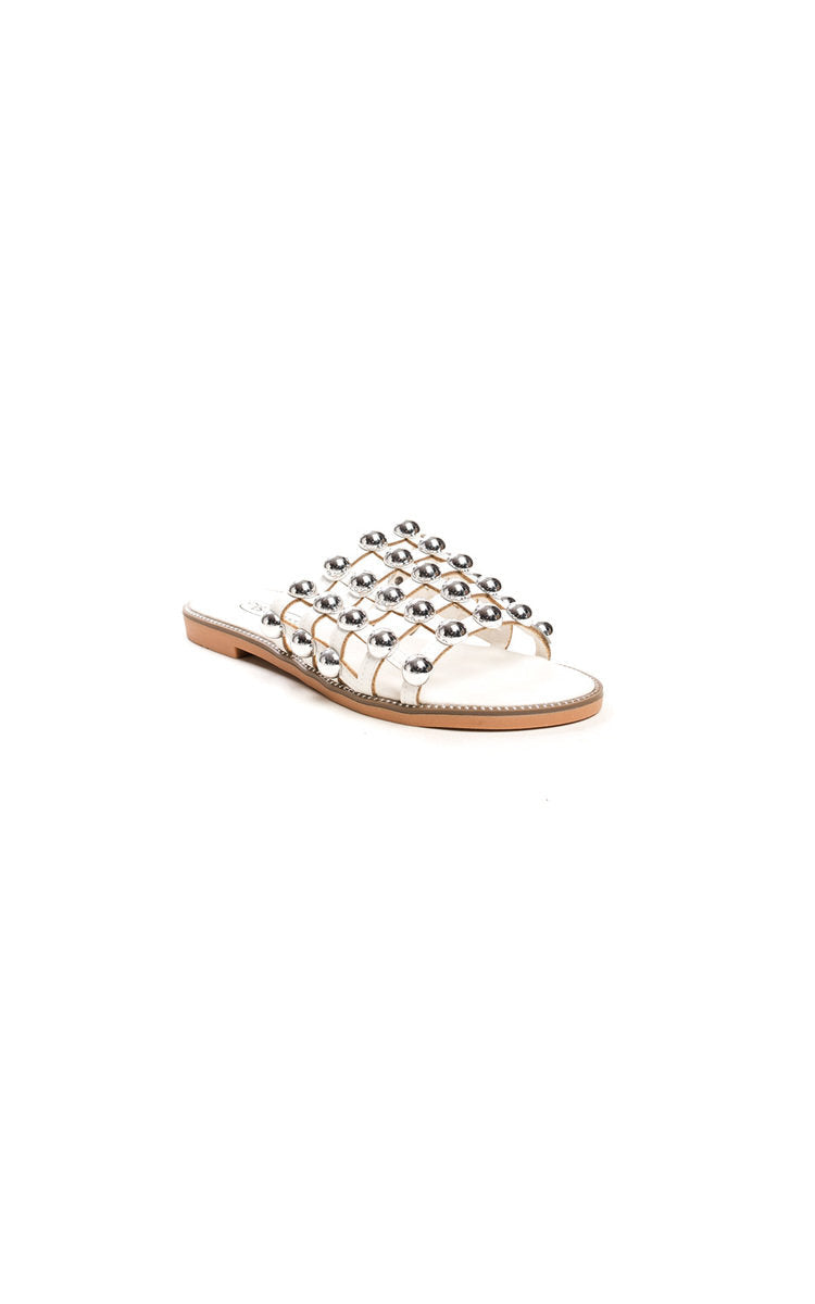 White flat slide sandals with silver studded lattice straps and open toe