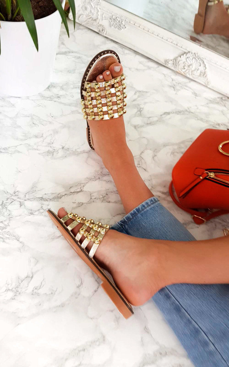 Nude flat slide sandals with studded lattice straps, open toe and low flat sole