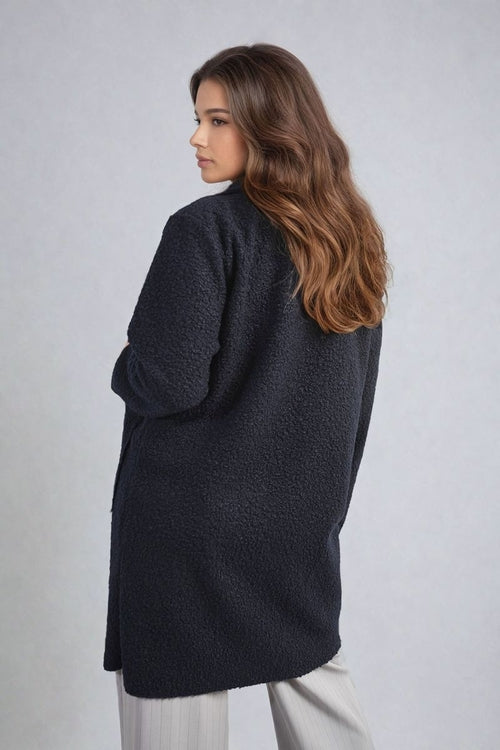 Dark textured button-front long jacket with front pockets and three-quarter sleeves.