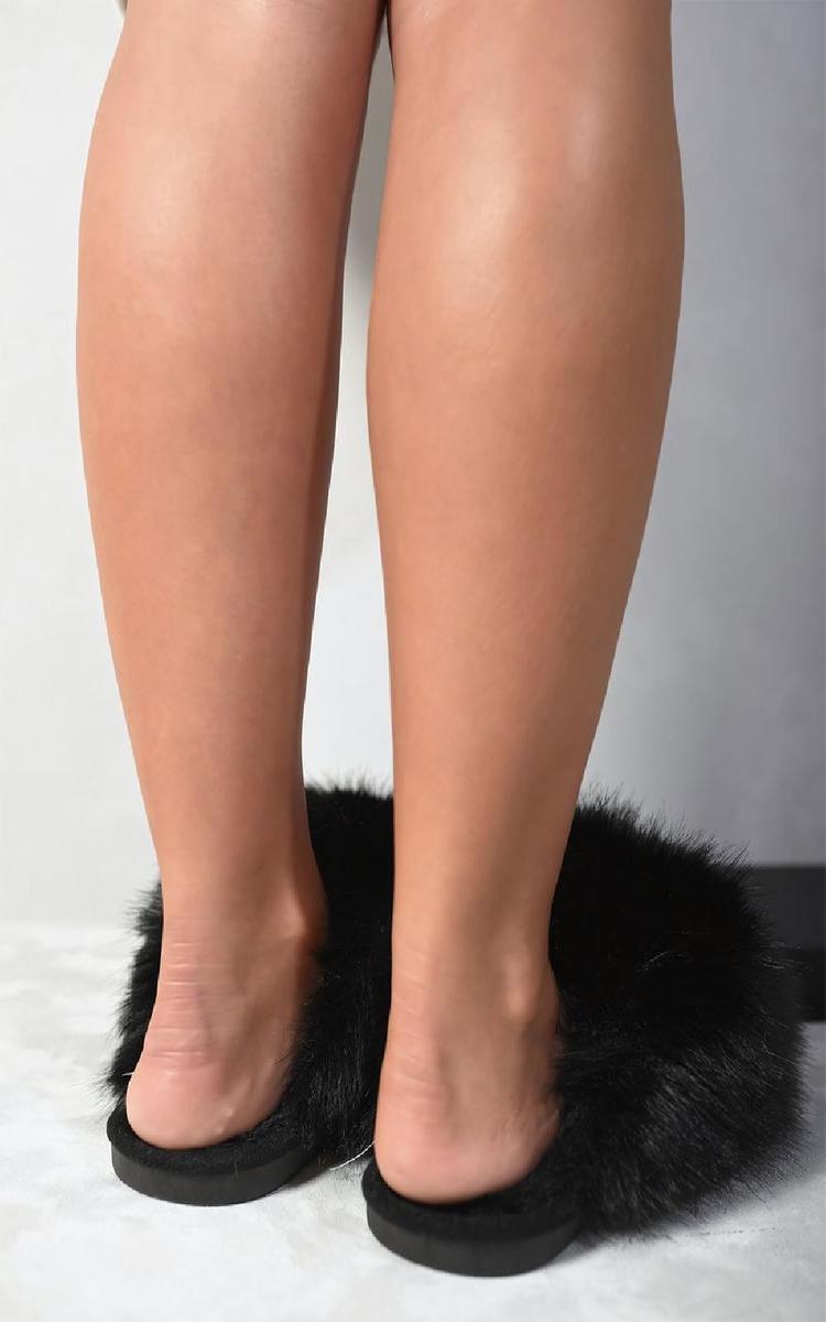 Black faux fur slippers with open back and cushioned sole, shown on a standing foot