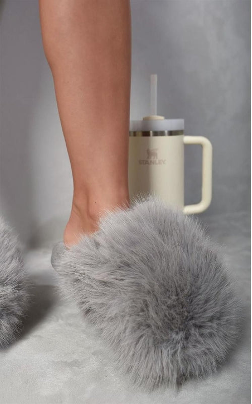 Grey faux fur open-back slippers with fluffy upper, shown stepping forward