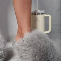 Grey faux fur open-back slippers with fluffy upper, shown stepping forward
