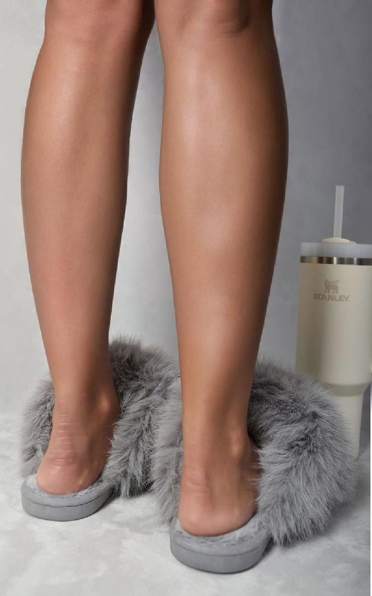Grey faux fur open-back slippers with low-profile sole, worn by a model