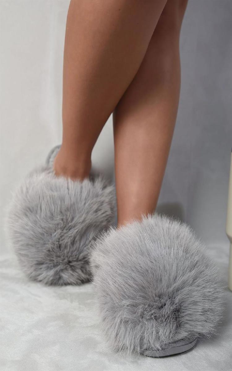 Grey faux fur open-back slippers with fluffy upper and flat sole on bare feet