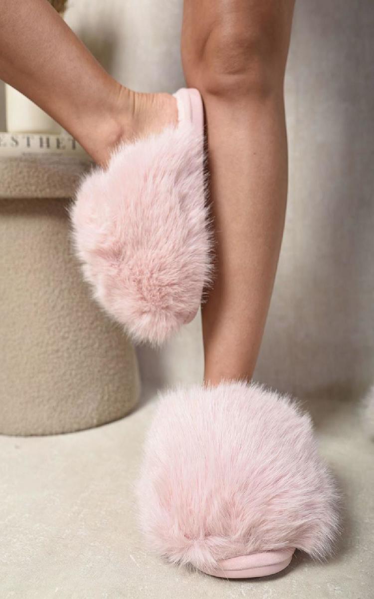 Pink fluffy open-back slippers worn with bare legs