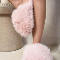 Pink fluffy open-back slippers worn with bare legs