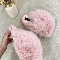 Pink fuzzy open-back slippers with soft fur uppers and black logo patch