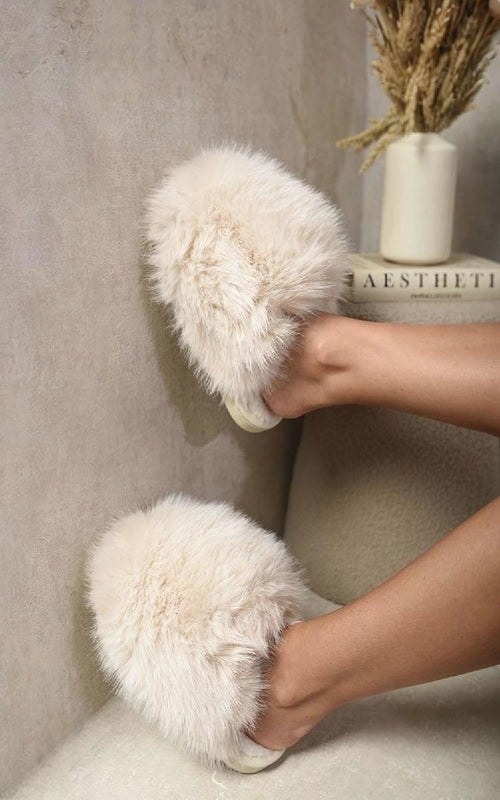 Cream faux fur open-back slippers, worn with visible soft slip-on design