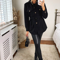 Black belted jacket with gold buttons, flap pockets, and long sleeves.