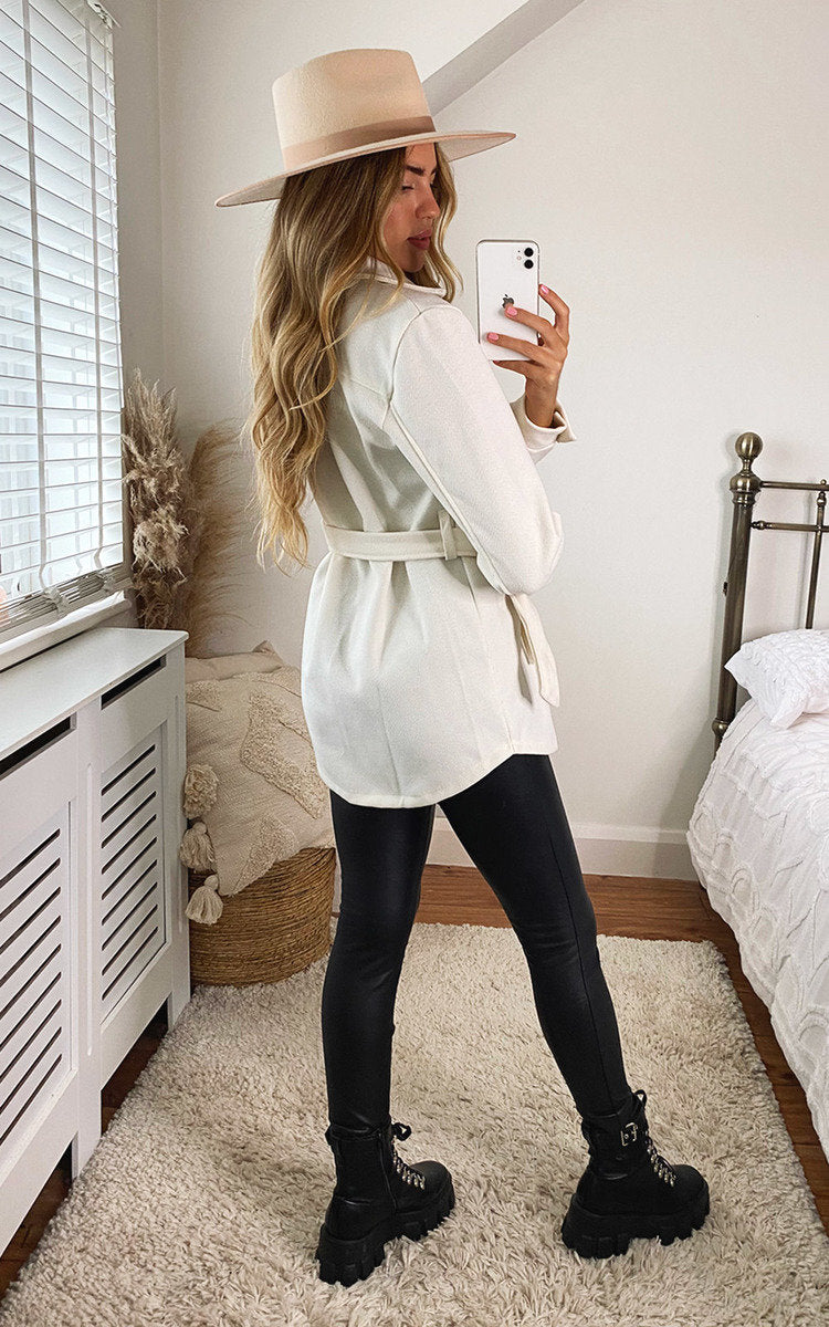 White belted jacket with gold buttons, flap pockets, and long sleeves.