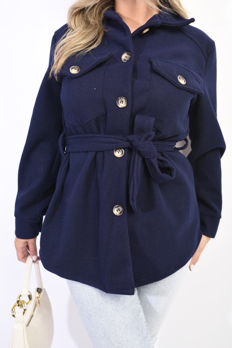 Navy belted jacket with button front, flap pockets, and roll-tab collar.