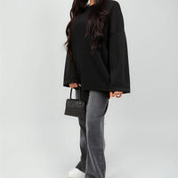 Oversized black sweatshirt with round neck and long sleeves, relaxed fit on model.