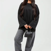Oversized black sweatshirt with round neck and long sleeves, loose fit with cuffs.