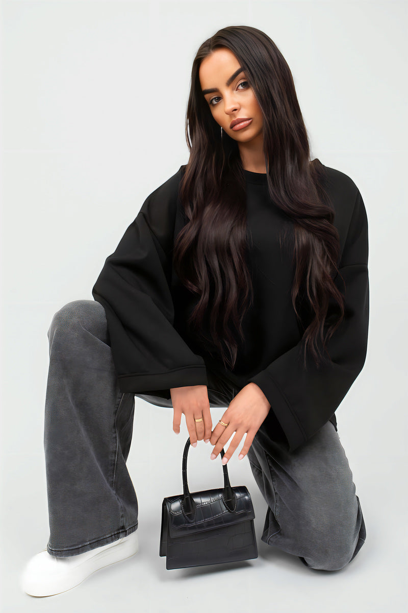 Oversized black sweatshirt with round neck and long sleeves, relaxed drape.