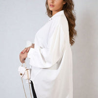 Oversized collared white button-down shirt with long puff sleeves and curved hem