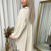 Beige collared button-down top with long sleeves, side drape, and back view