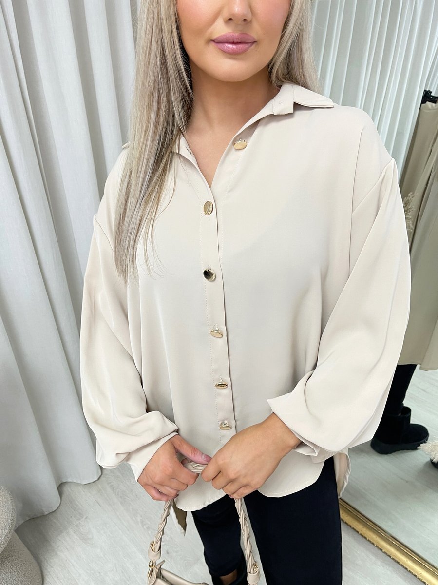 Beige collared button-down top close-up with gold-tone buttons and partial placket