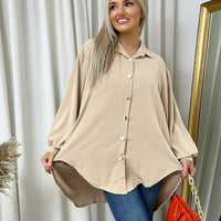 Oversized collared beige button-down shirt with long puff sleeves and rounded hemline