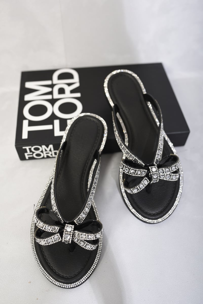 Black flat sandals with rhinestone bow and toe-post straps, paired