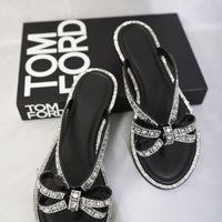 Black flat sandals with rhinestone bow and toe-post straps, paired