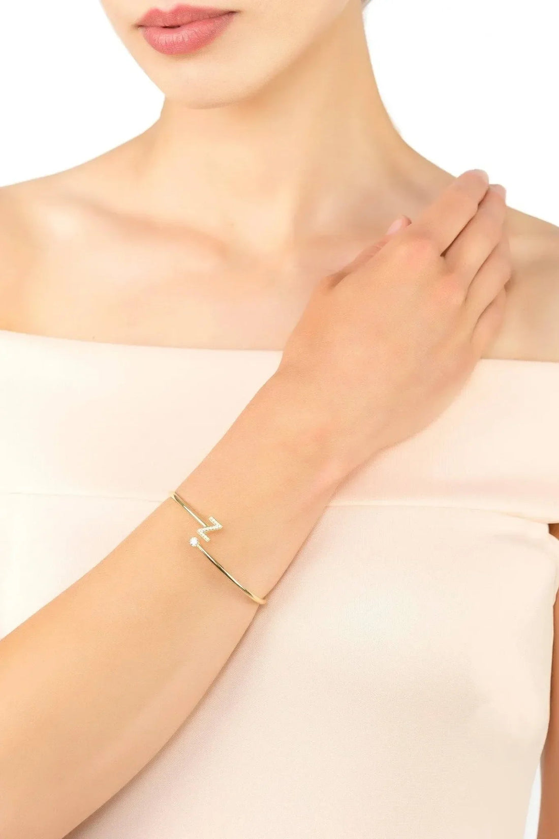 Gold-tone bangle bracelet on wrist with initial Z and crystals