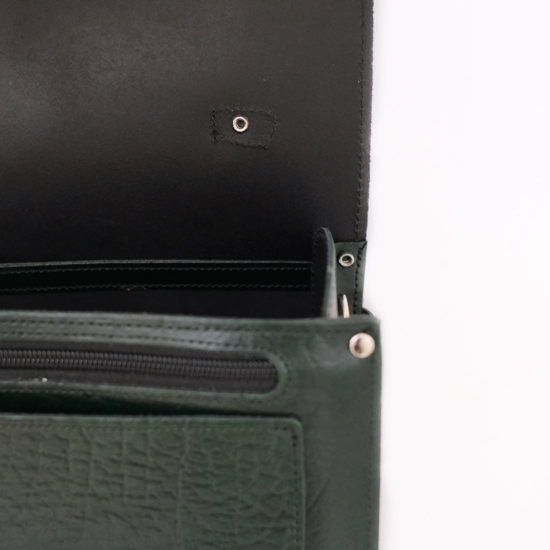 Green leather satchel close-up showing zipper and interior pocket lining