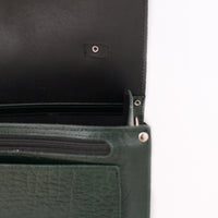 Green leather satchel close-up showing zipper and interior pocket lining