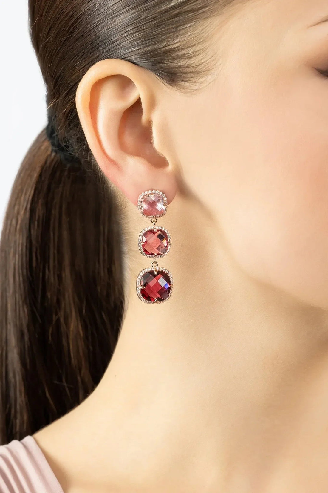 Rose gold earrings with pink, red, and dark red faceted stones in tiered drops
