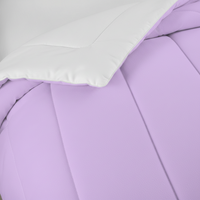 Pastel lavender comforter close-up with smooth quilted panels and white pillow edge