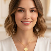 Gold zodiac talisman necklace with round Libra pendant and blue crystal, worn on neckline