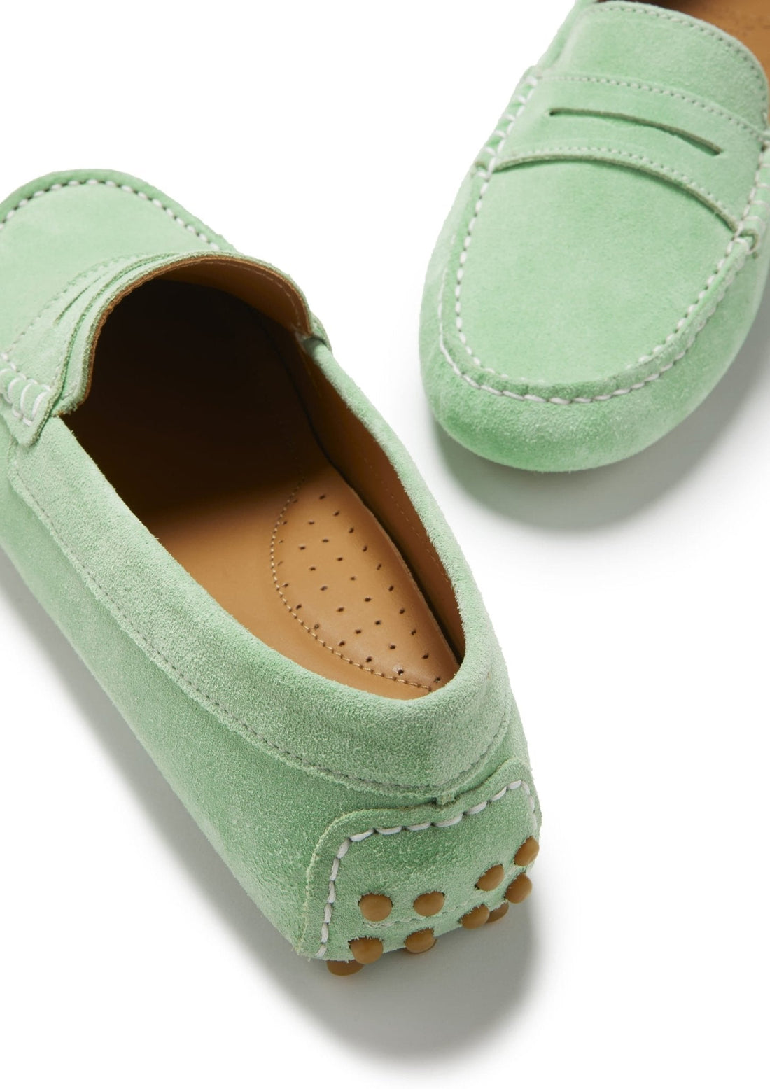 Green suede driving loafer close-up showing tan perforated insole and rubber heel studs.