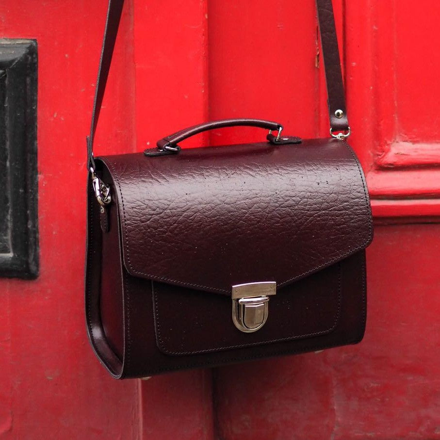 Marsala red leather satchel with top handle, shoulder strap, and front buckle clasp
