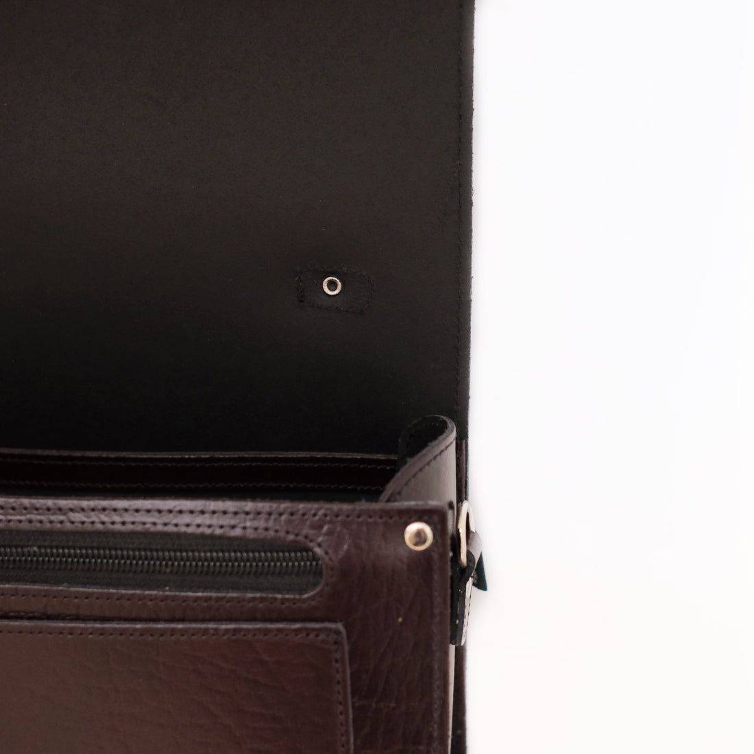 Dark leather bag close-up with zipper pocket and metal rivets on front panel