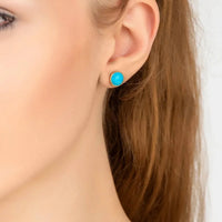 Gold hoop earrings with round turquoise gemstone, shown on ear