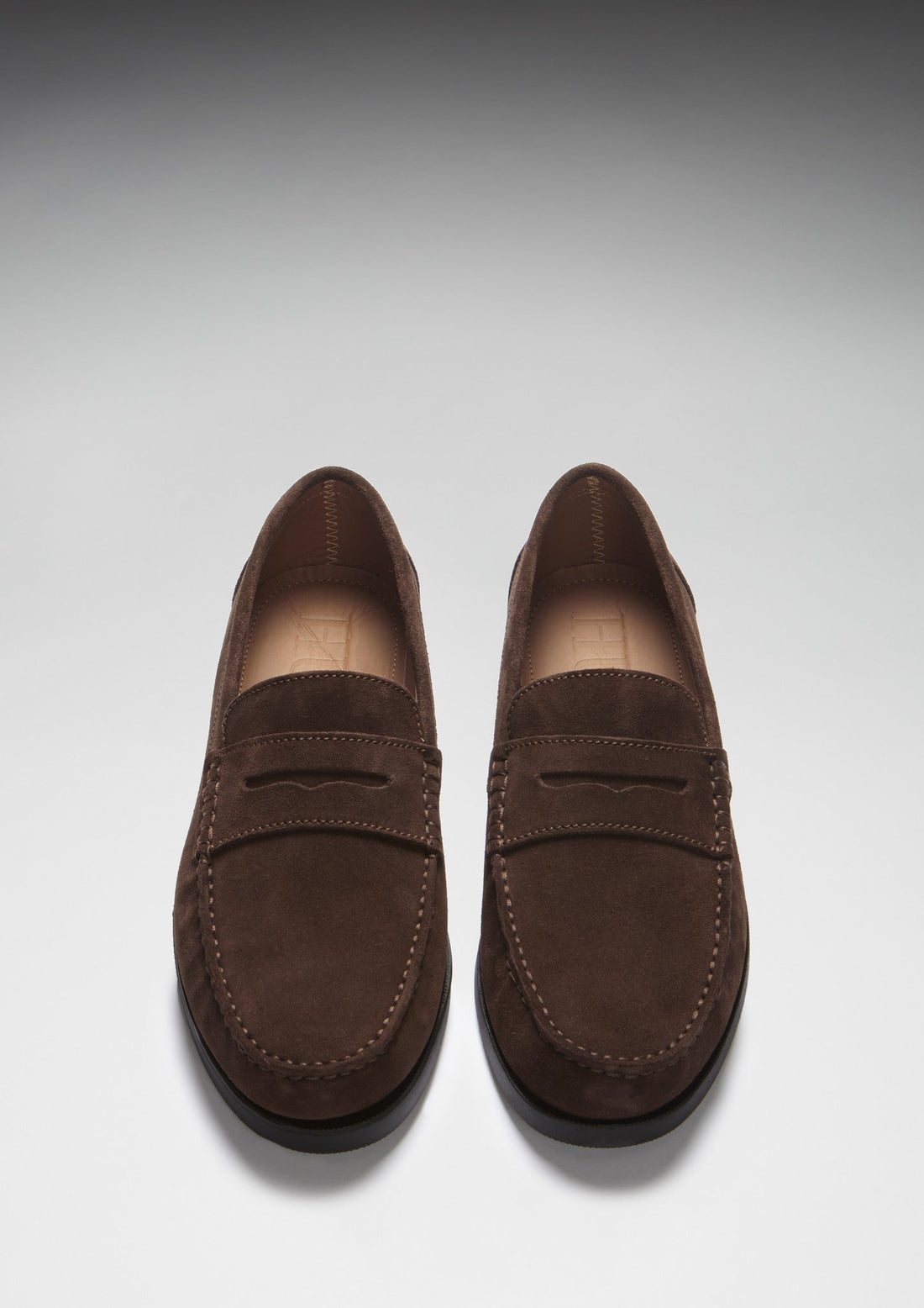 Pair of brown suede loafers shown from above, with stitched toes and penny straps