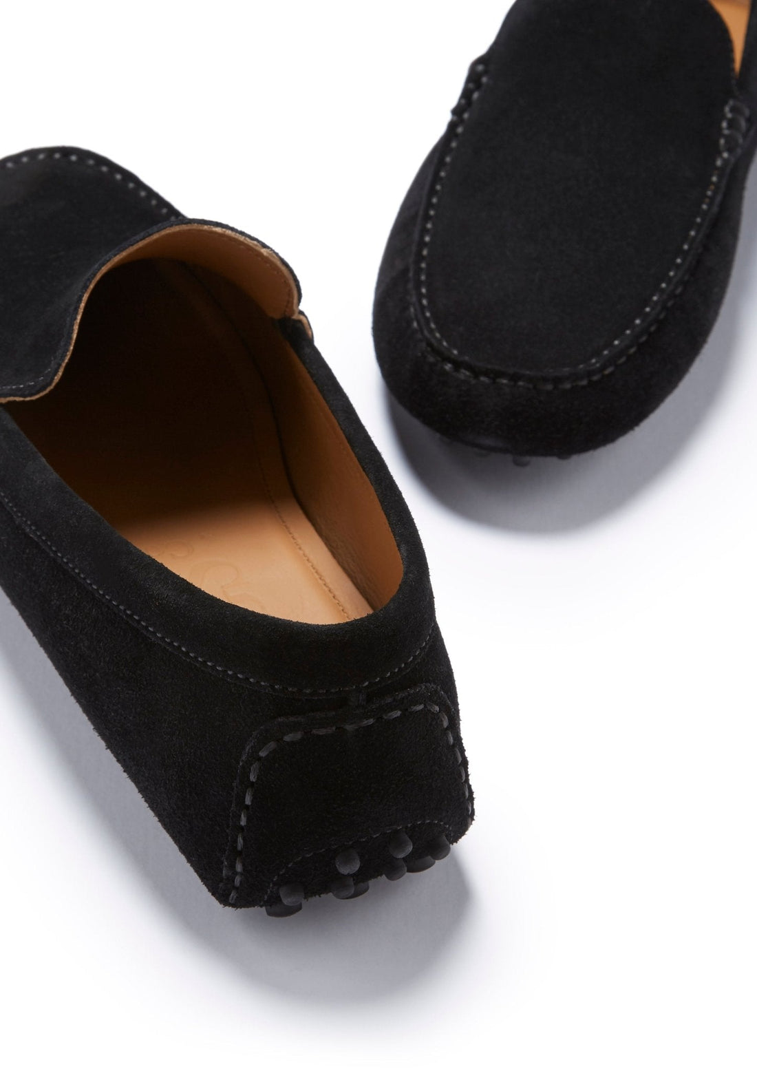 Black suede driving loafers showing the moc toe stitching, heel details, and tan lining.