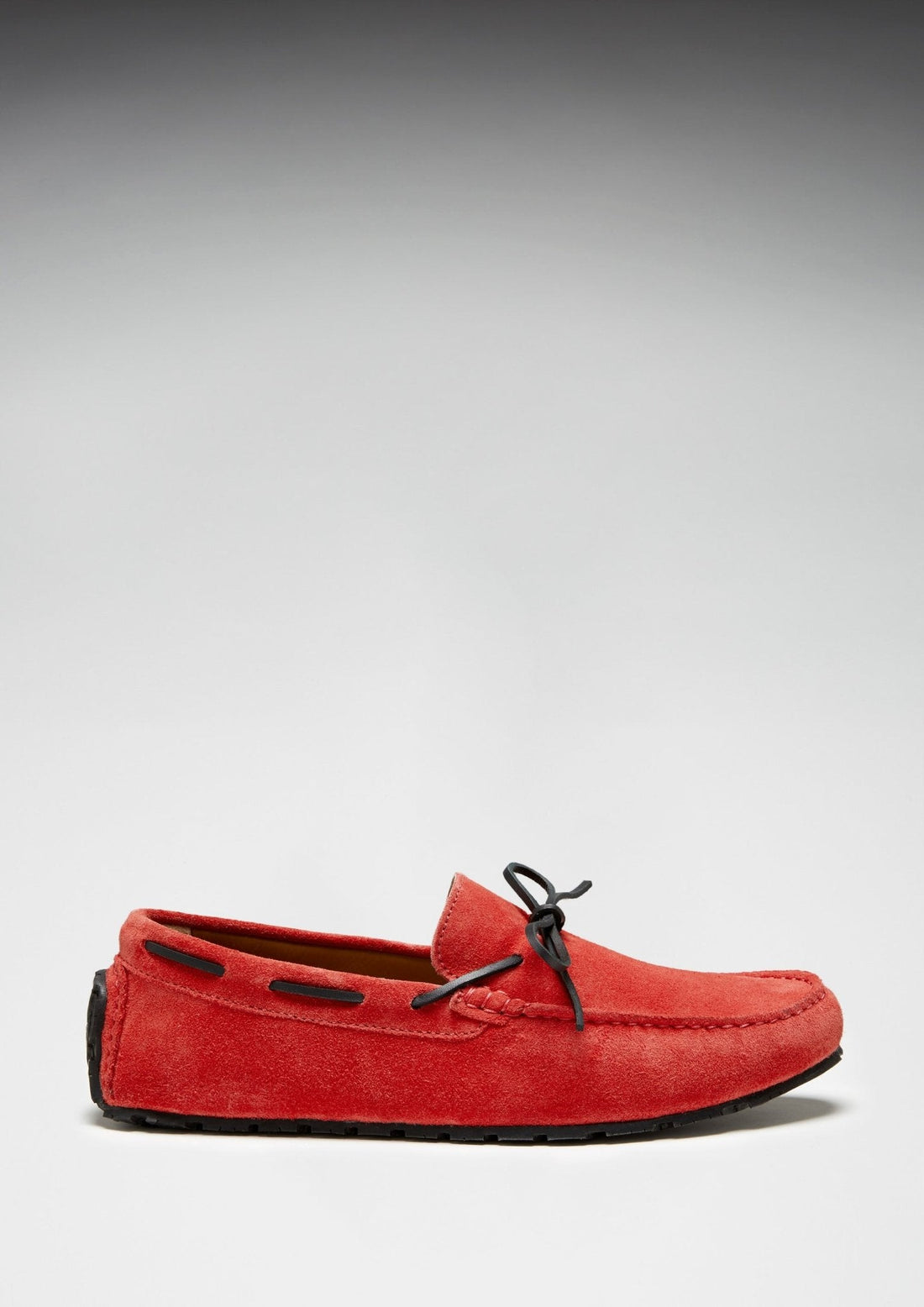 Red suede loafer with black lacing and a side view of its low-profile sole