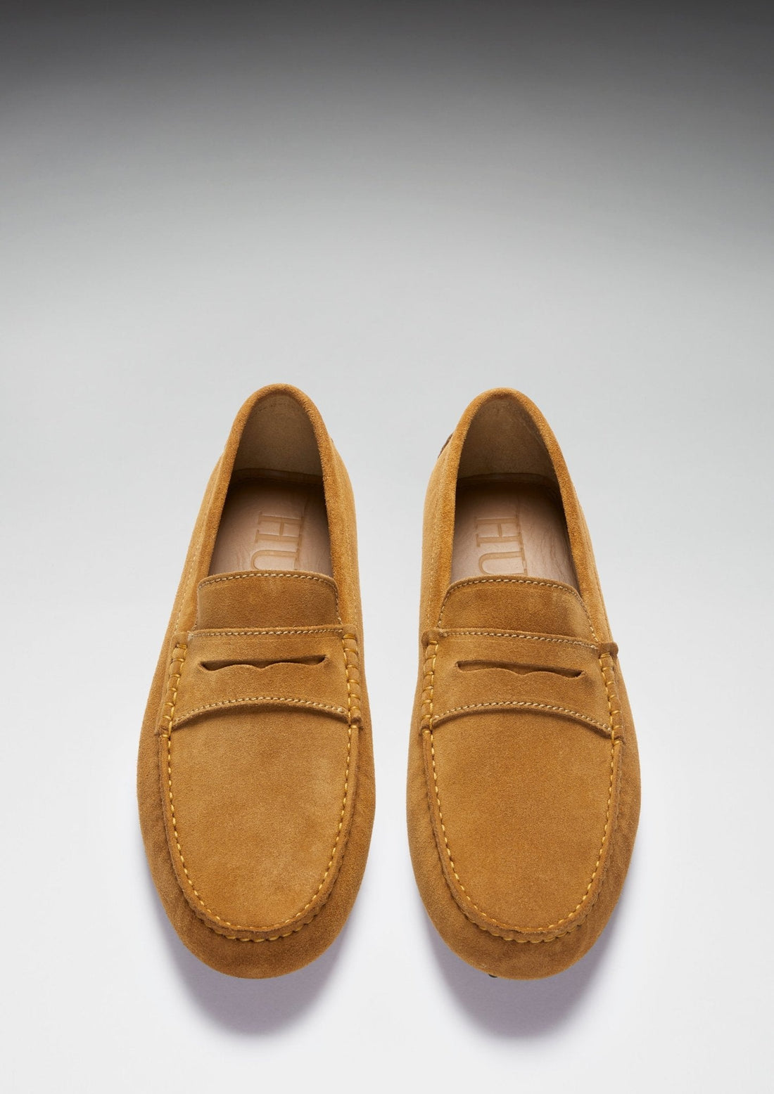 Pair of tan suede loafers viewed from above, showing penny straps and rounded toes.