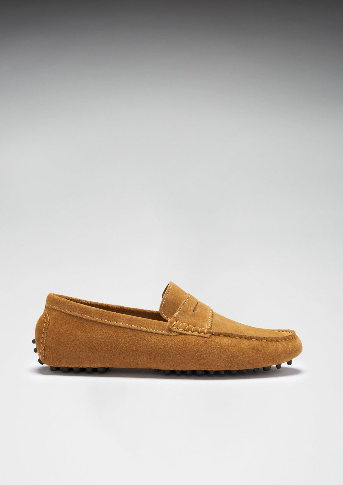 Side profile of a tan suede penny loafer with a low rubber pod sole.