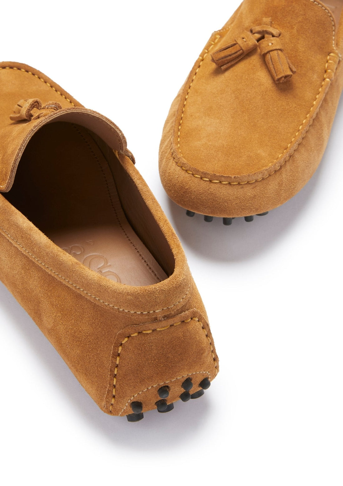Tan suede loafer close-up showing tassels, moc stitching, and rubber heel studs