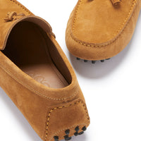 Tan suede loafer close-up showing tassels, moc stitching, and rubber heel studs