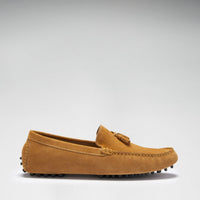 Side view of a tan suede driving loafer with tassel detail and rubber stud sole