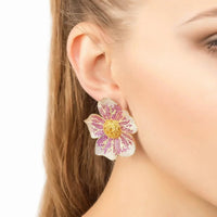Beaded flower earrings on ear with pink and purple petals and gold-tone posts.