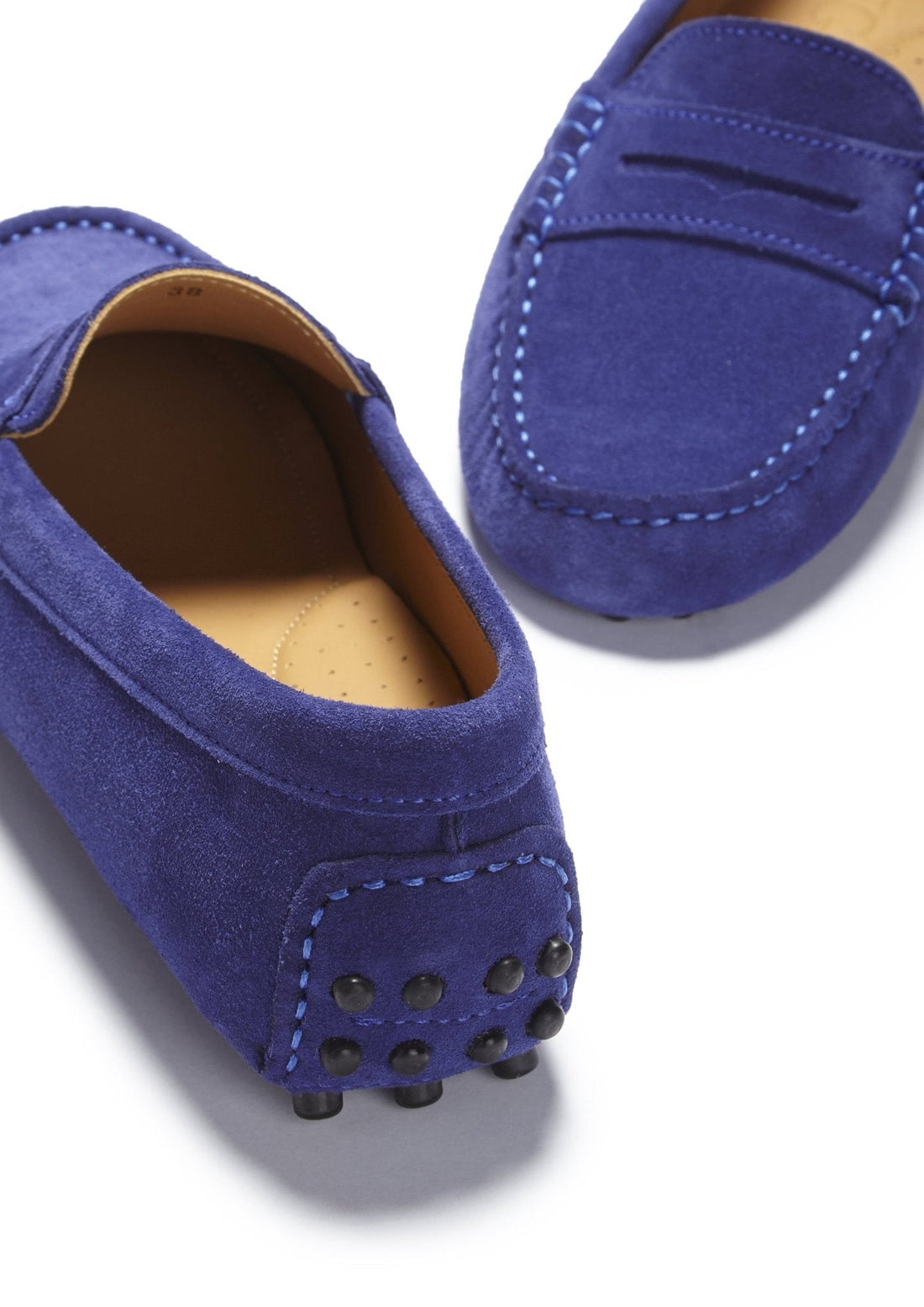 Suede loafer detail showing heel studs, stitched toe, and tan lining