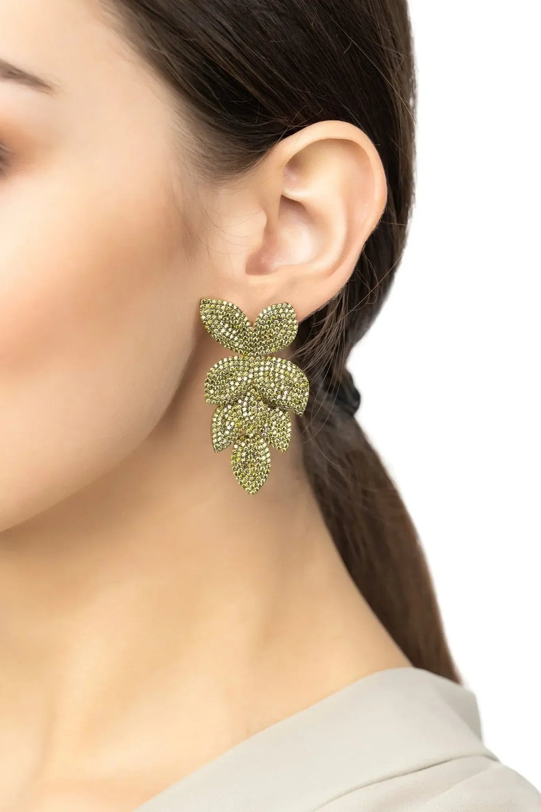 Green peridot CZ flower drop earrings on a model’s ear, gold-tone posts
